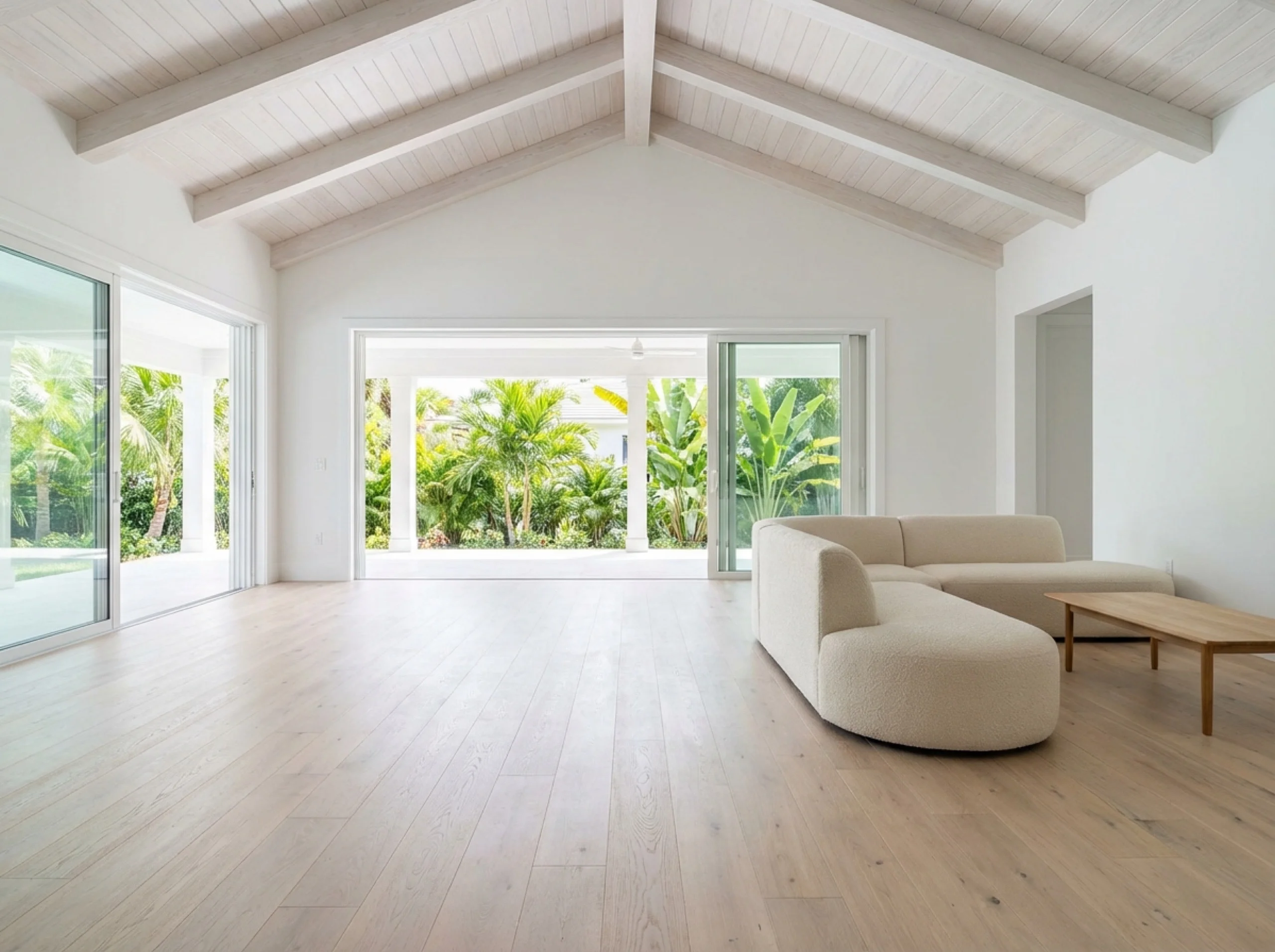 Wide-plank wire-brushed white oak engineered hardwood in a modern coastal great room with sliding doors to a lanai