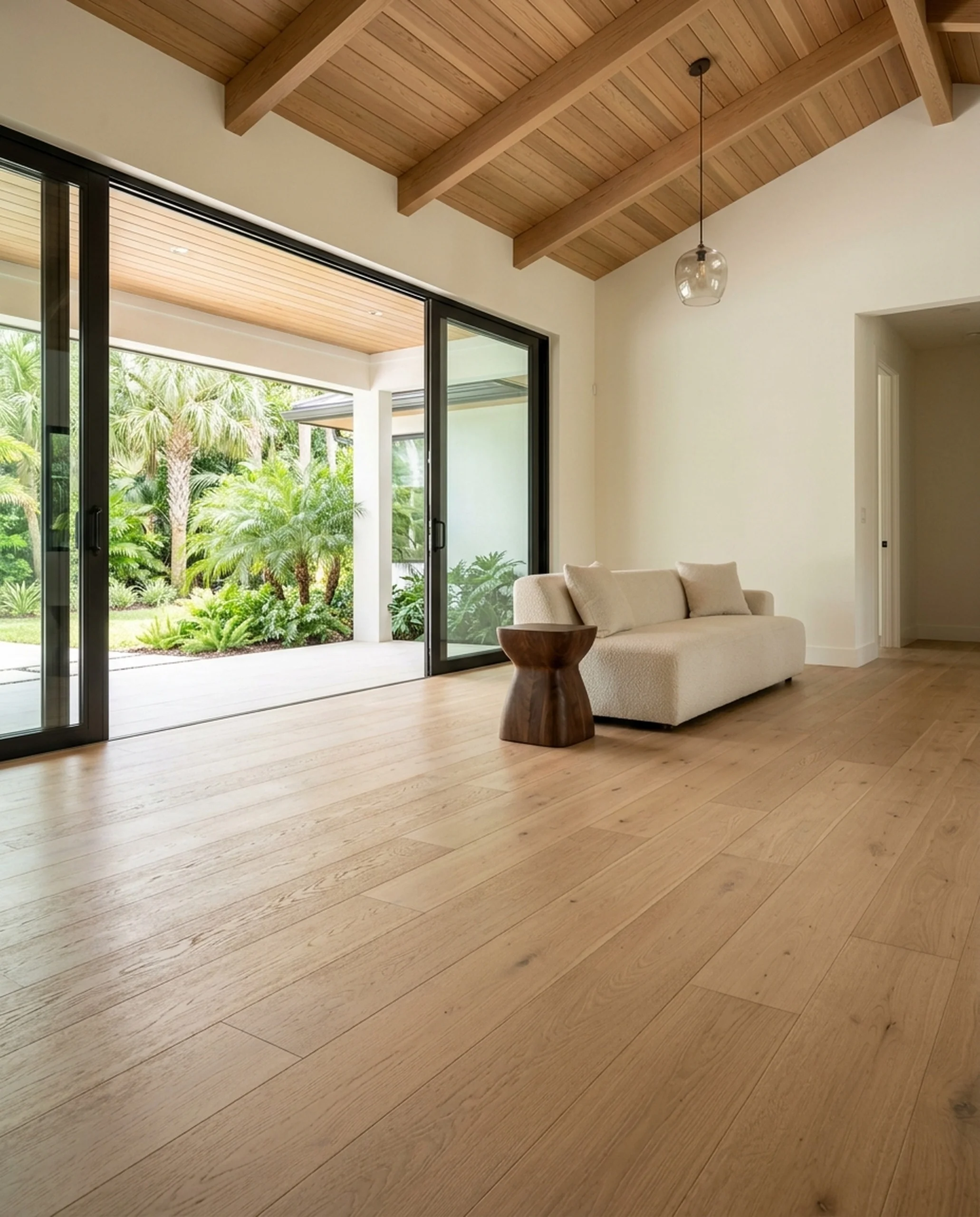 Wide-plank European white oak engineered hardwood in a modern coastal great room with sliding doors to a lanai